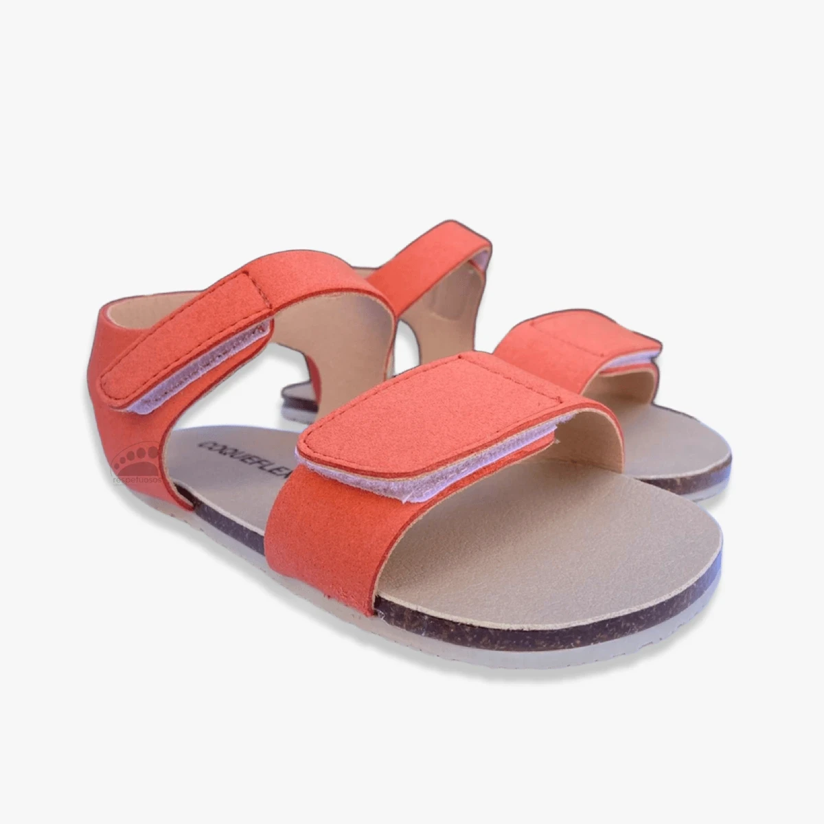 Sandalia barefoot Coqueflex coral con cierre de velcro, vista frontal en ángulo que resalta la amplitud de la puntera y plantilla recta.