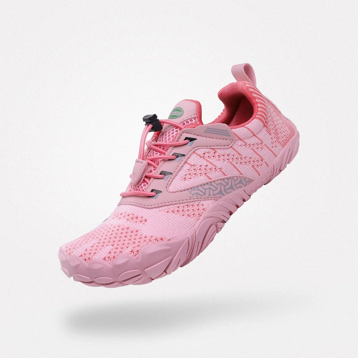 Zapatilla minimalista tipo barefoot de la marca Saguaro en tonos rosas, con tejido transpirable, cierre elástico y suela flexible, vista lateral suspendida.